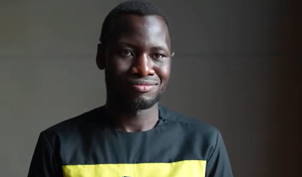 Preview image for the video "Oroma Kenneth -  #ZeroDiscriminationDay - Teach For Uganda" - Tight headshot of a young black man in a black t-shirt.