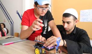 Two teenage boys in hats build a robot vehicle