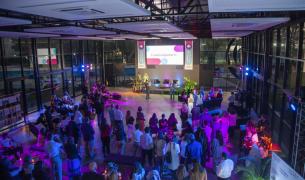 A crowd looks at a screen that says Ensena por Argentina in a large event space with many windows