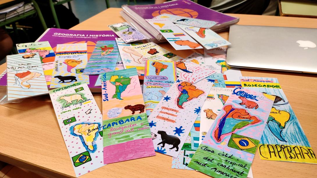 A collection of colorful, hand-drawn maps indicating where capybaras live spread out on a table